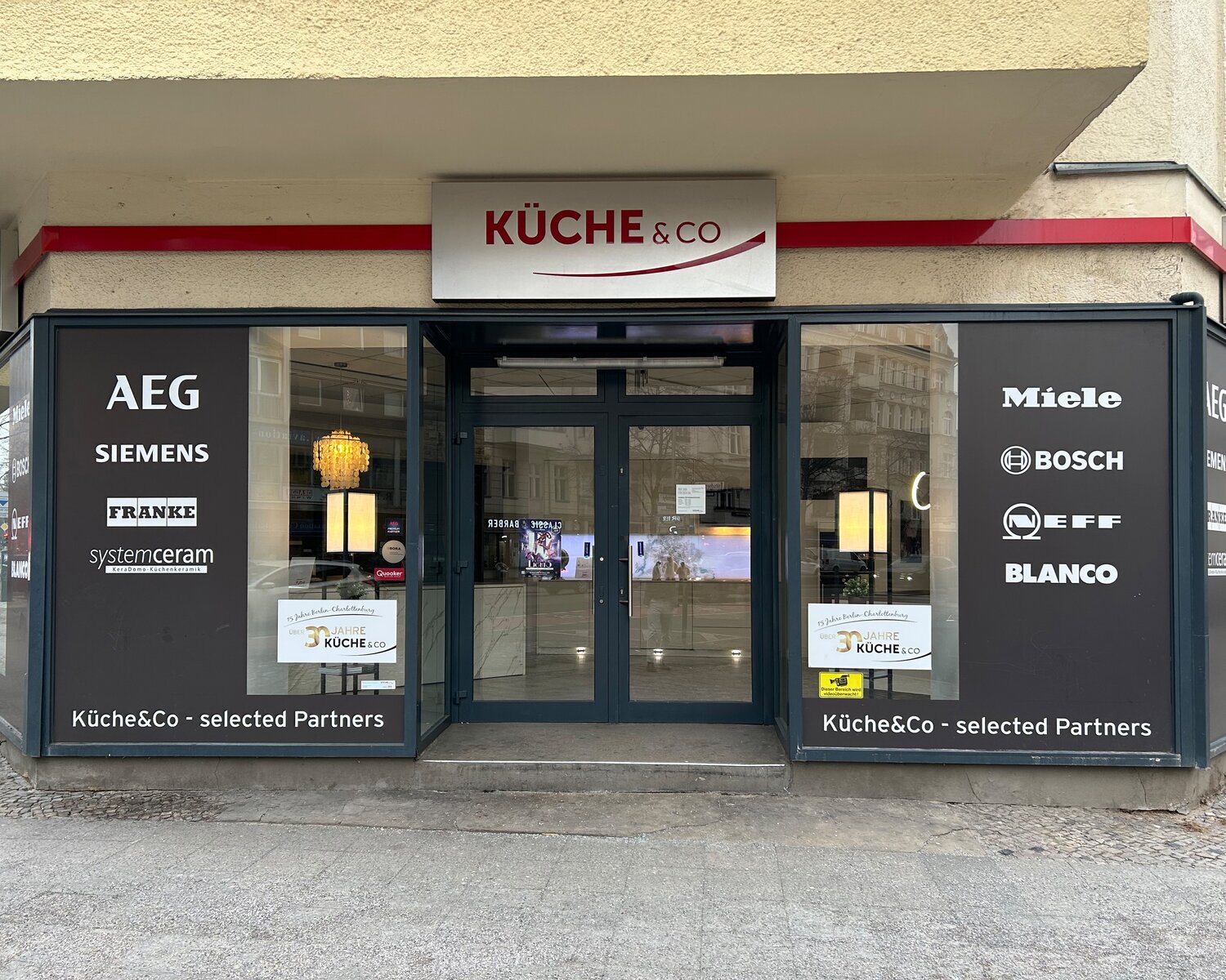Ladenlokal von Küche&Co in Berlin-Charlottenburg mit Firmenschild und Gerätemarken im Schaufenster