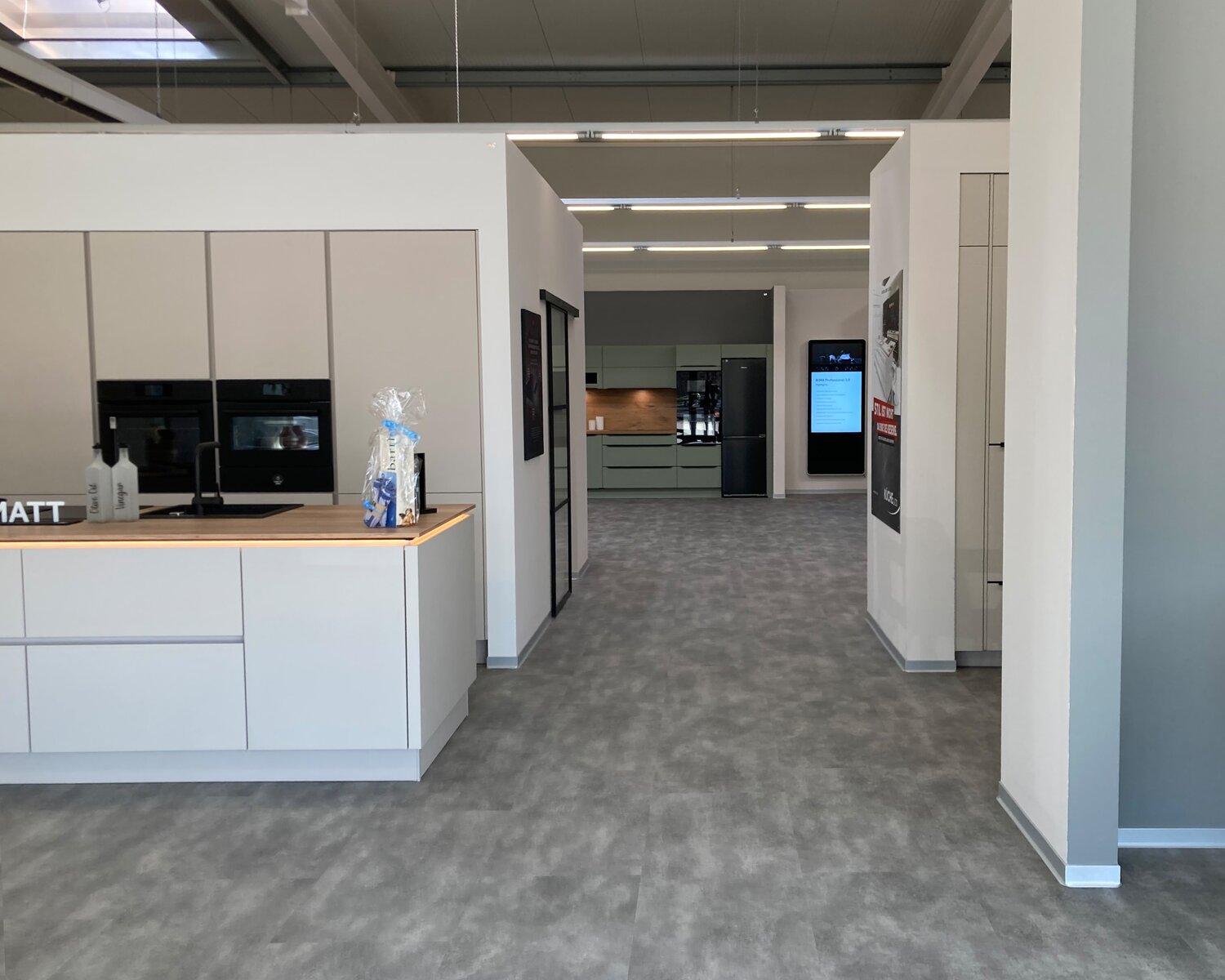 Ausstellungsfläche mit weißer Küchenzeile und Gerätehochschränken im Küche&Co-Studio Halle